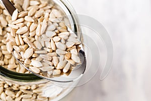 A spoon filled wiht sunflower seeds on a glass jar