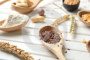Spoon with flax seeds on white wooden table, closeup