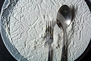 Spoon and fork against the background of white gypsum with a microrelief of various shapes. For a menu or article about