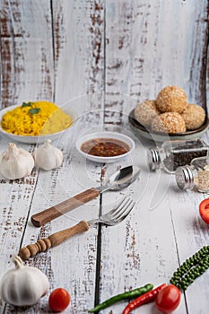 Spoon, fork and chili sauce in white cup with spices on a white wooden floor