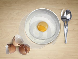 Spoon fork fried egg on plate on a Cream background
