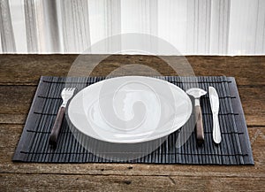 Spoon, fork, knife and white dish on Platemat photo