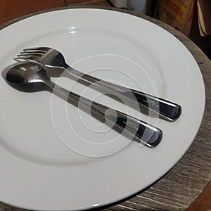 spoon and fork on white dinner plate