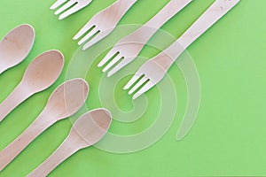 Spoon and forks setup Cutlery on a bright green background. Eco-friendly wooden disposable cutlery on bright colored backdrop.