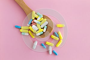 Spoon full of pills on pink background. Addiction concept.