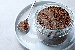 Spoon and glass jar with instant coffee on light table, closeup