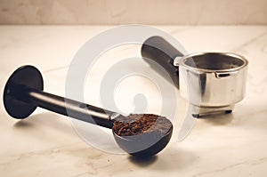 spoon with ground coffee and holder/black spoon with ground coffee and holder on marble background, selective focus