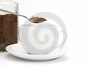 Spoon of instant coffee granules with cup