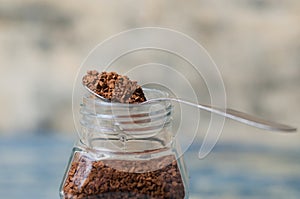 Spoon with instant coffee over the can closeup. Coffee granules macro