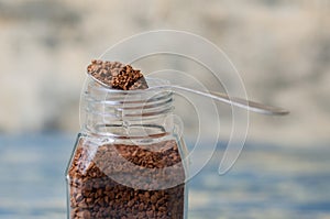 Spoon with instant coffee over the can closeup. Coffee granules macro