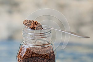 Spoon with instant coffee over the can closeup. Coffee granules macro