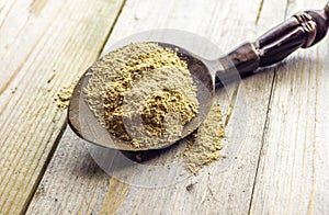 Spoon with Kava Kava root powder on wooden table closeup