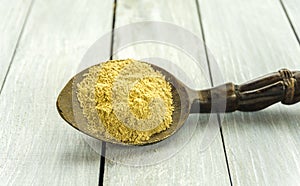 Spoon with Kava Kava root powder on wooden table closeup