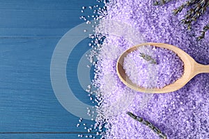 Spoon with lilac sea salt and lavender flowers on blue wooden table, flat lay. Space for text