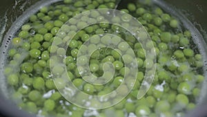 Spoon mixing peas in water close-up
