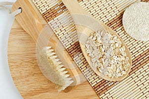 Spoon with oatmeal and wooden massage body brush. Natural beauty treatment and zero waste concept. Flat lay, copy space