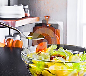 Spoon with olive oil on italian fresh salad and tomato on wood kitchen