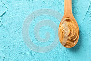 Spoon with peanut butter on color background, space for text