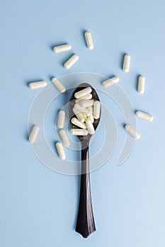Spoon with pills on a blue background. Medicine. Medication. Health
