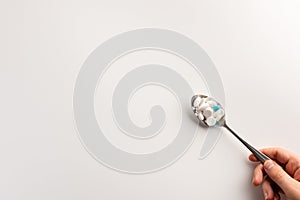 Spoon with pills in the hand, isolated on white background