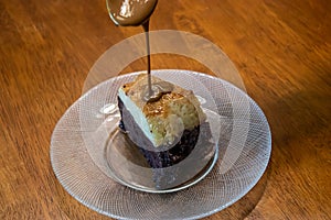 Spoon pouring caramel de leche over slice of cake