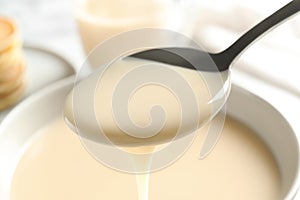 Spoon of pouring condensed milk over bowl. Dairy products