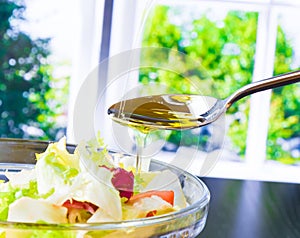 Spoon with pouring olive oil on italian fresh salad