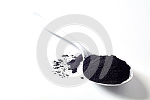 Spoon of round activated black plant charcoal photo