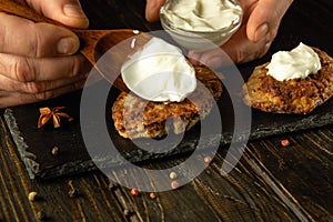 Spoon with sour cream in the hand of the cook. Preparing a snack dish with cutlets and sour cream. Food serving concept