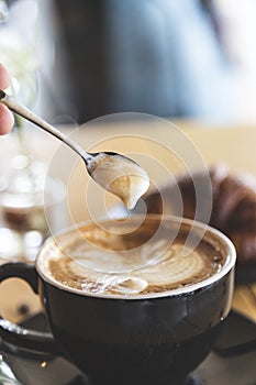 Spoon stirring coffee in a hipster coffee shop. Relaxed and classy atmosphere