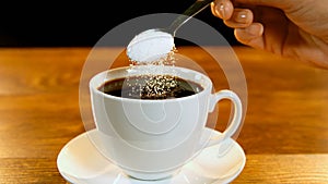 Spoon of sugar poured into coffee cup