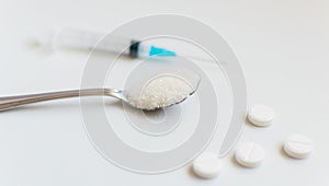 A spoon of sugar, a syringe and pills. The concept of harm to sugar and the onset of diabetes.