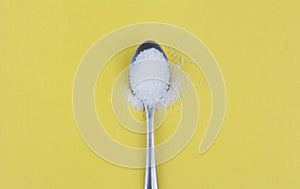 Spoon of sugar on yellow background