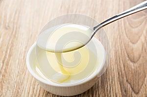 Spoon with sweet condensed milk above glass bowl