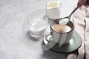 Spoon with sweetener over a cup of milk coffee