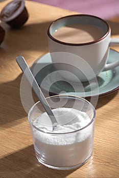 Spoon in sweetener stevia on a background of coffee with milk