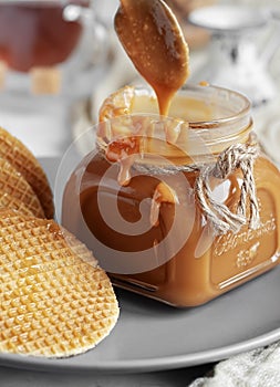 Spoon with tasty caramel sauce over jar on table. Selective Focus, Vertical Orientation. Close-up