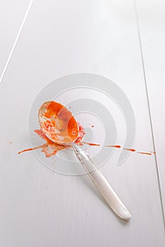 Spoon with tomato sauce splash on white table