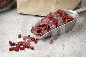 Spoon withf dried Iranian barberries in front of a paper bag