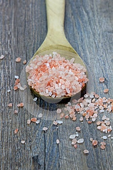 Spoonful of Pink Himalayan Salt on Rustic Wood Background with t