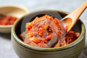 spooning spicy red kimchi onto plain rice bowl