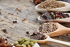 Spoons with aromatic various spices for cooking on old wooden board, close-up, flat lay, selective focus.