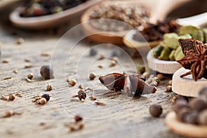 Spoons with aromatic various spices for cooking on old wooden board, close-up, flat lay, shallow depth of field.