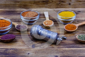 Spoons and bowls with oriental spices and spice mill on a wooden table