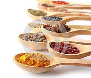 Spoons with different dry spices on white background