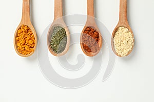 Spoons with different powder spices on white background