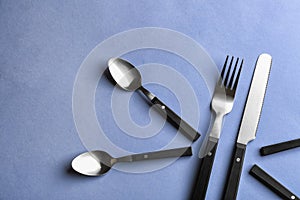 Spoons, fork and knife on color background