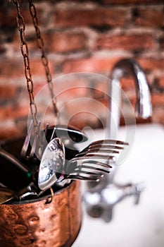 Spoons and forks are put in containers that hang in the sink.