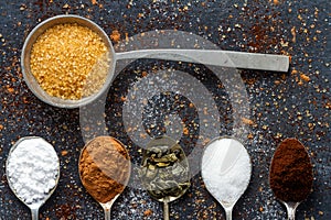 Spoons with icing sugar, green tea, coffee and cocoa on black background sprinkled with sugar, coffee, cocoa powder