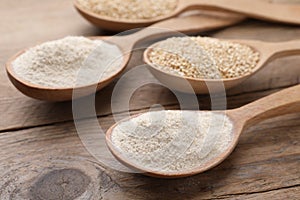 Spoons with quinoa flour and seeds on wooden table, closeup